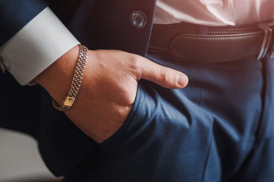 A sophisticated man in a business suit, showcasing his style with a subtle touch of luxury—a gold bracelet peeking out from his pocket, adding a refined and elegant detail to his ensemble