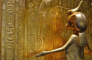 Golden Statue of Egyptian Goddess with Bird Headdress Embracing Hieroglyph-Adorned Wall