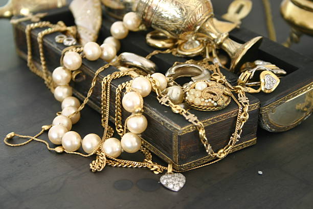 A vintage jewelry box overflowing with an assortment of elegant pearl necklaces, gold bracelets, and intricately designed chains